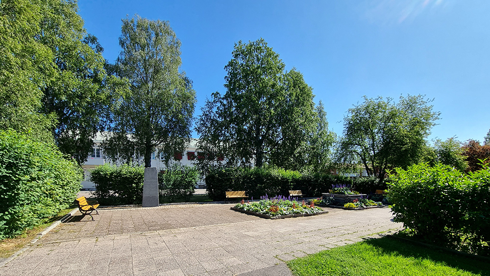 En öppen stenlagd yta med sommarplanteringar och sittplatser