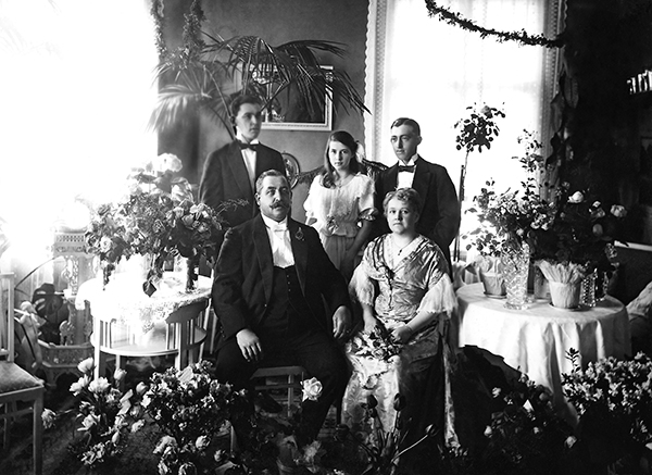 Porträtt av familj med blombuketter omkring sig.