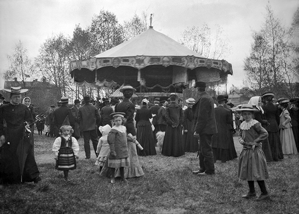 Barn i folkvimmel framför karusell