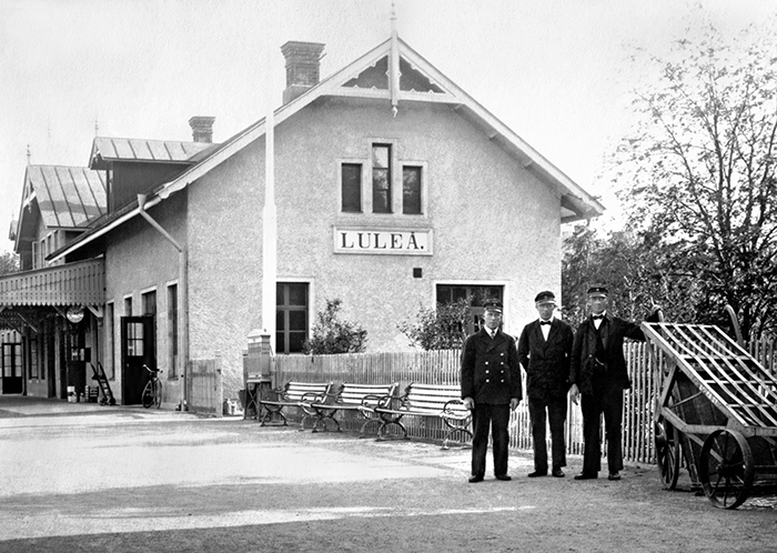 Tre män i uniform framför stationshuset.