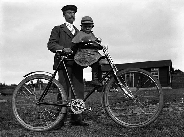 Agabus Björk stående vid cykel med liten pojke sittande på cykelramen.