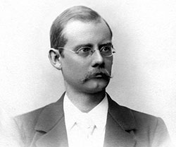 Foto av ung man med glasögon och mustasch.