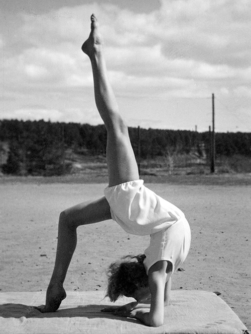 Kvinnlig gymnast i akrobatisk pose med ett ben rakt upp.