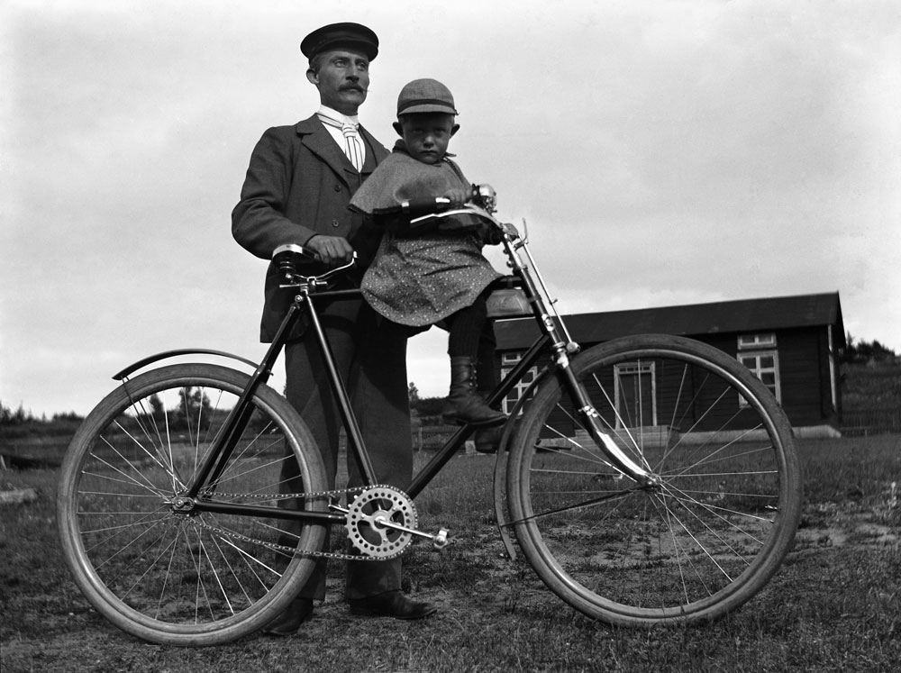 Agabus Björk poserar med cykel och ett litet barn sittande på ramen.