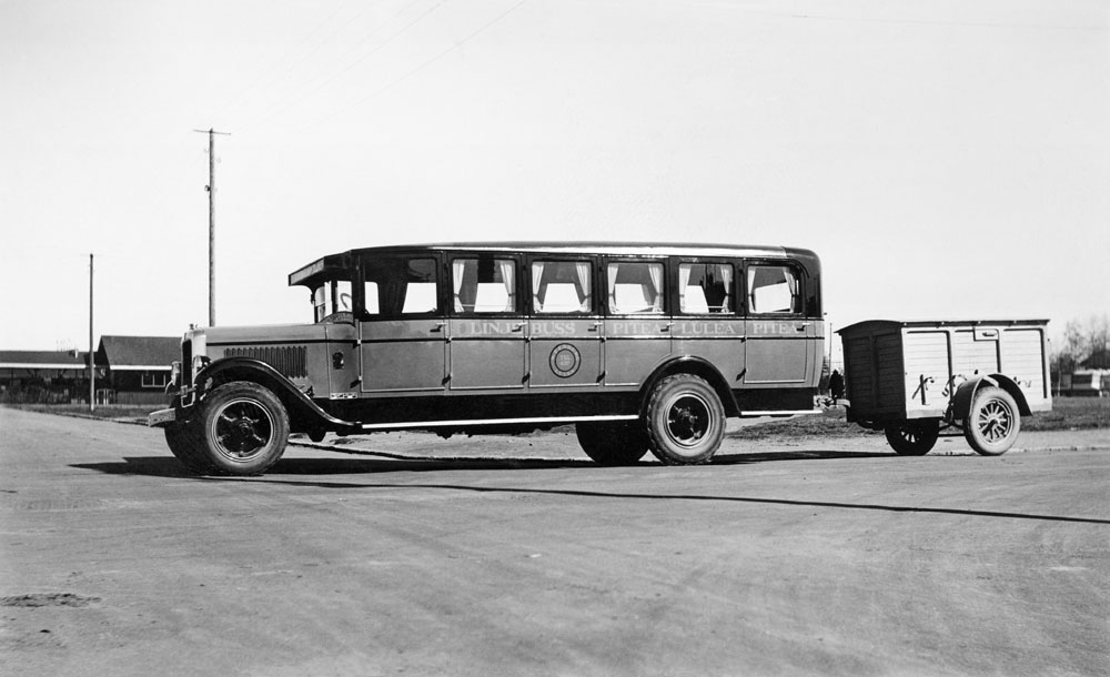 Buss av äldre modell med släpvagn bakom.
