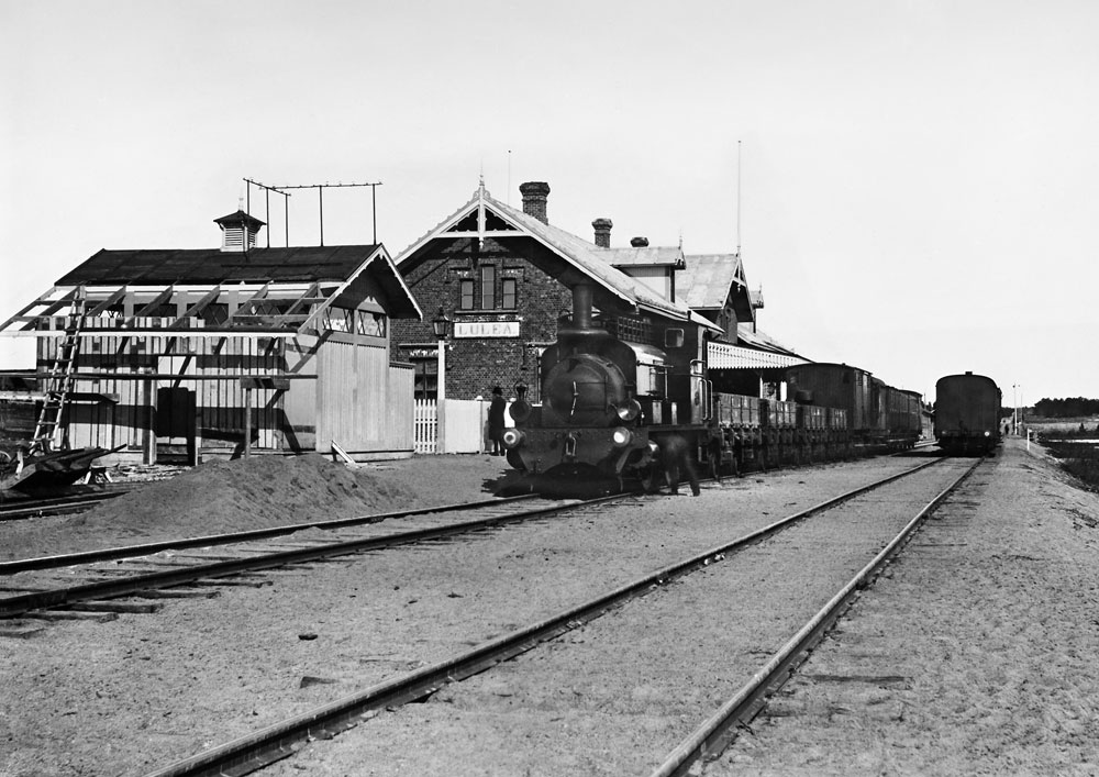 Ånglok med tåg vid järnvägsstationen.