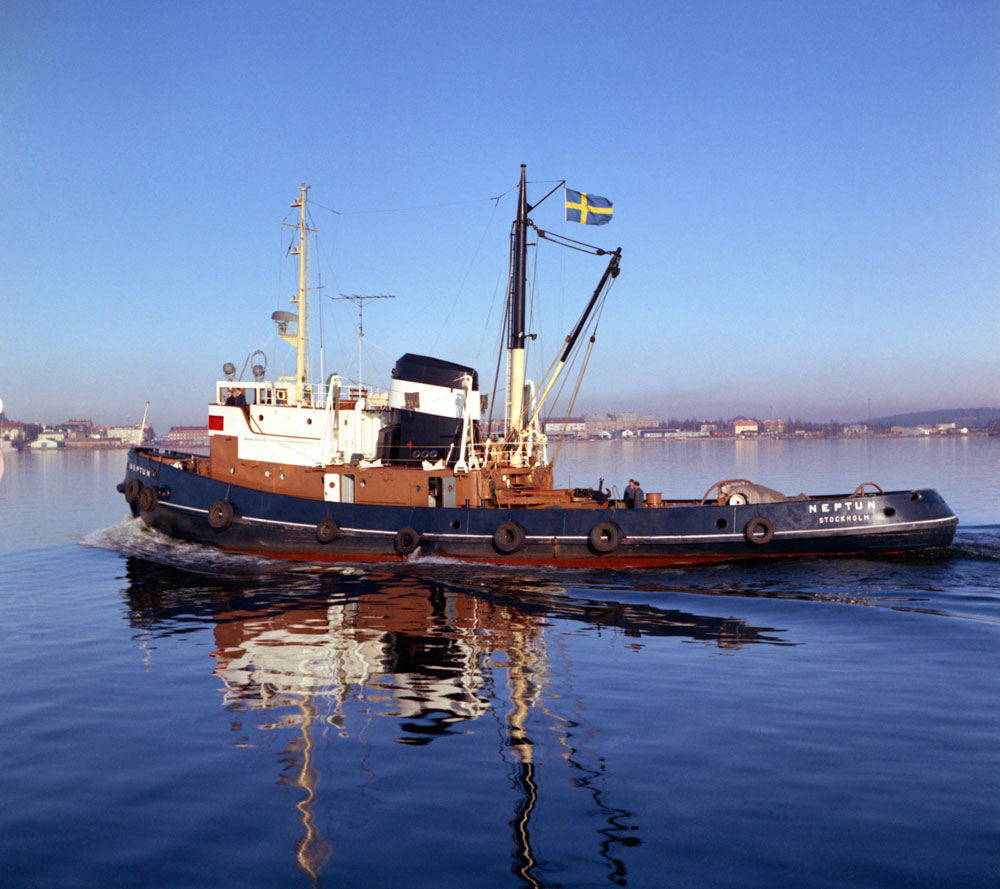 Bogserbåt av äldre modell med svensk flagga hissad.