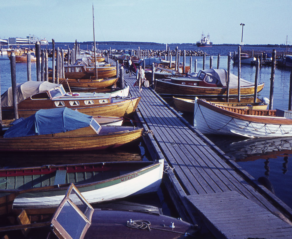 Småbåtshamn med många träbåtar vid brygga.