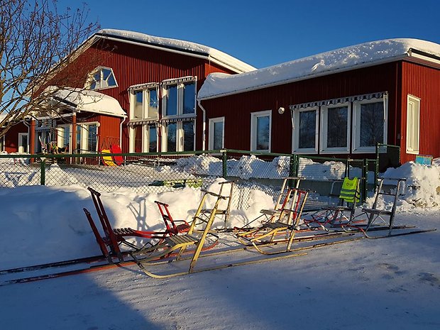 Utomhusbild Klöverträskskolan vintertid. Snösparkar står parkerade utanför skolan.
