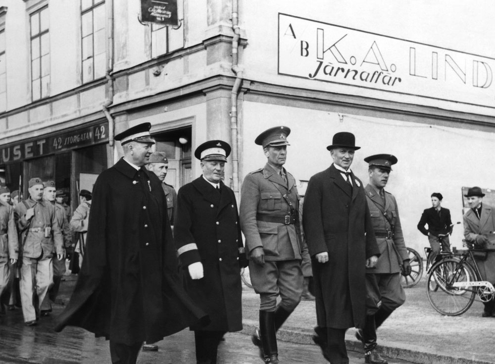 Fem män i uniform går i bredd på Luleågata