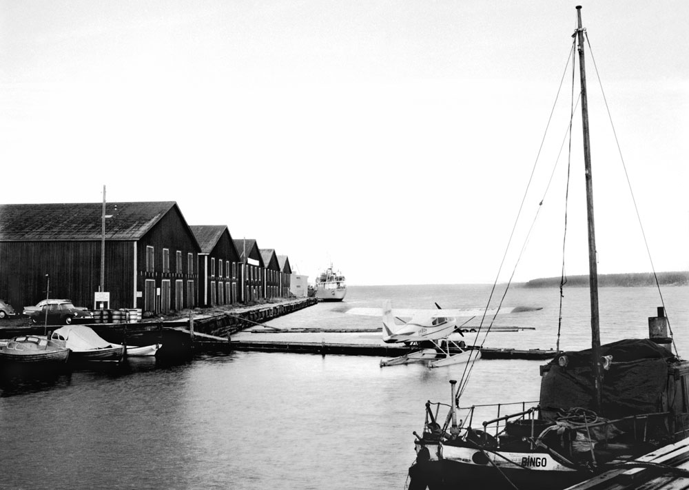 Hamnmiljö med hamnmagasin och båt vid kaj.