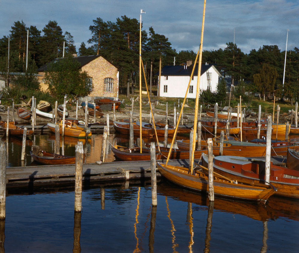 Småbåtshamn med flera träbåtar vid en brygga.