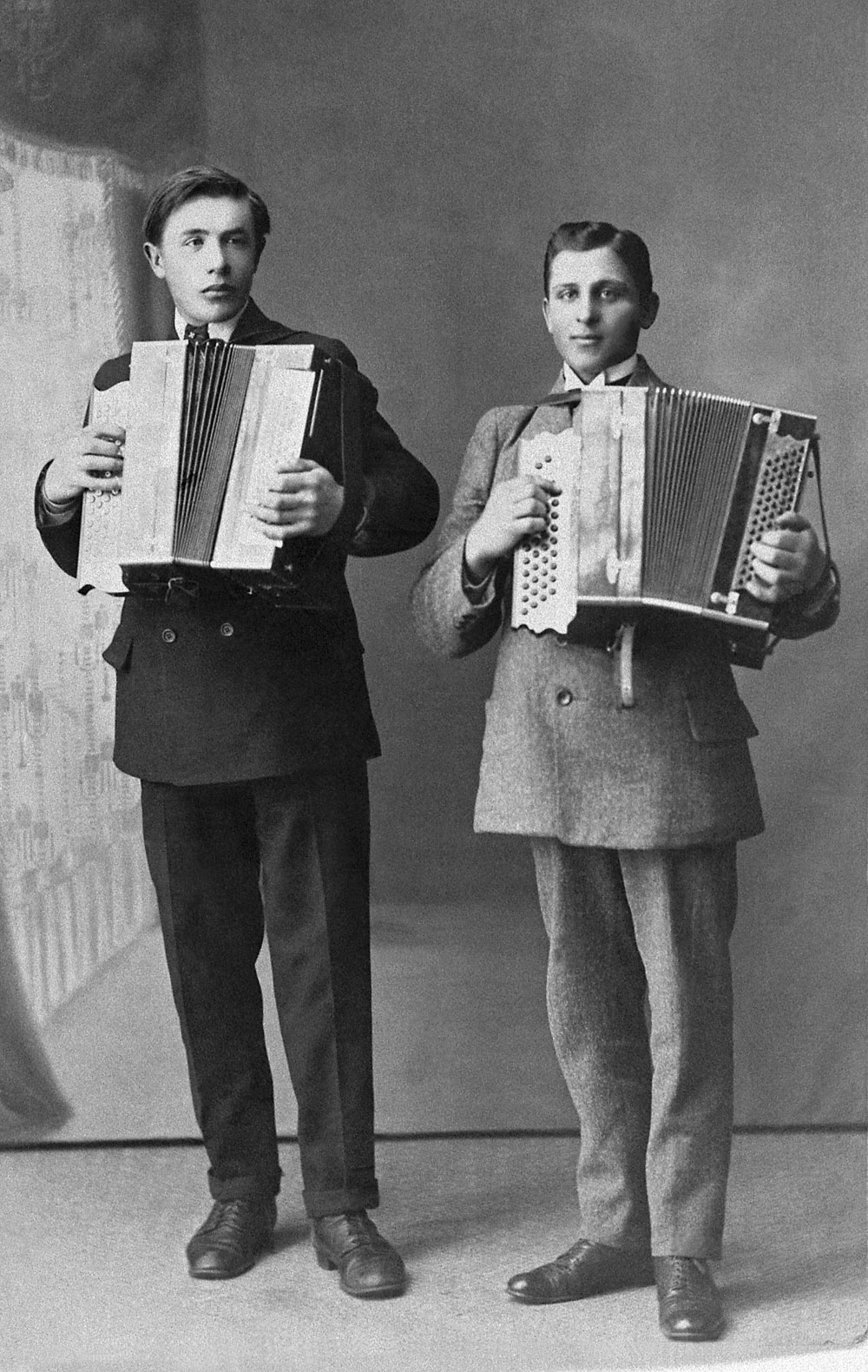 Två unga män i kostym stående med var sitt dragspel.