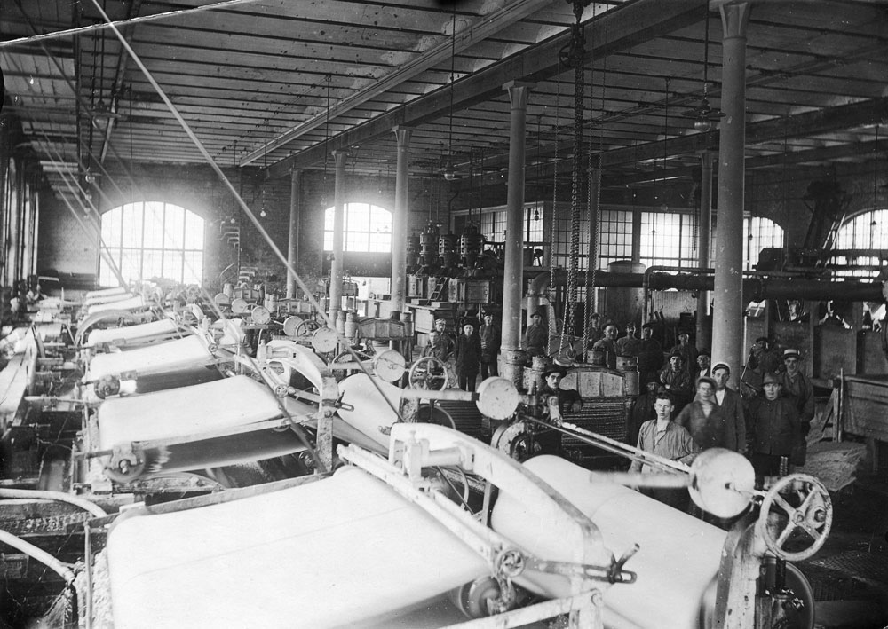 Interiör från en fabrikslokal med stora pappersmaskiner.