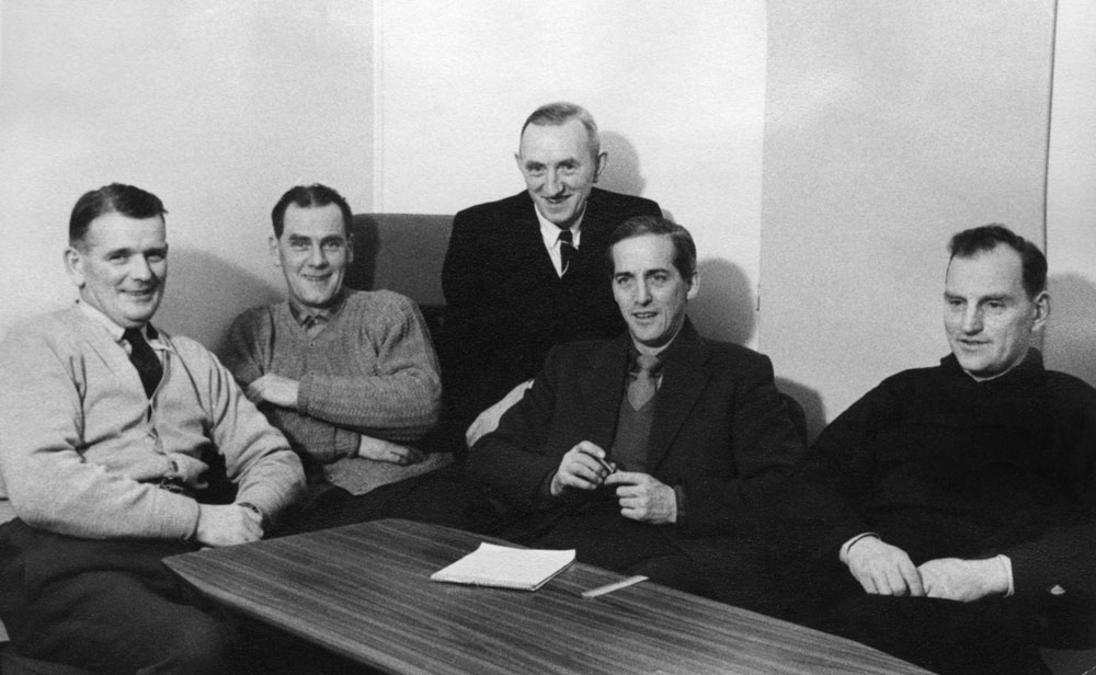 Gruppbild av fem män vid ett bord.