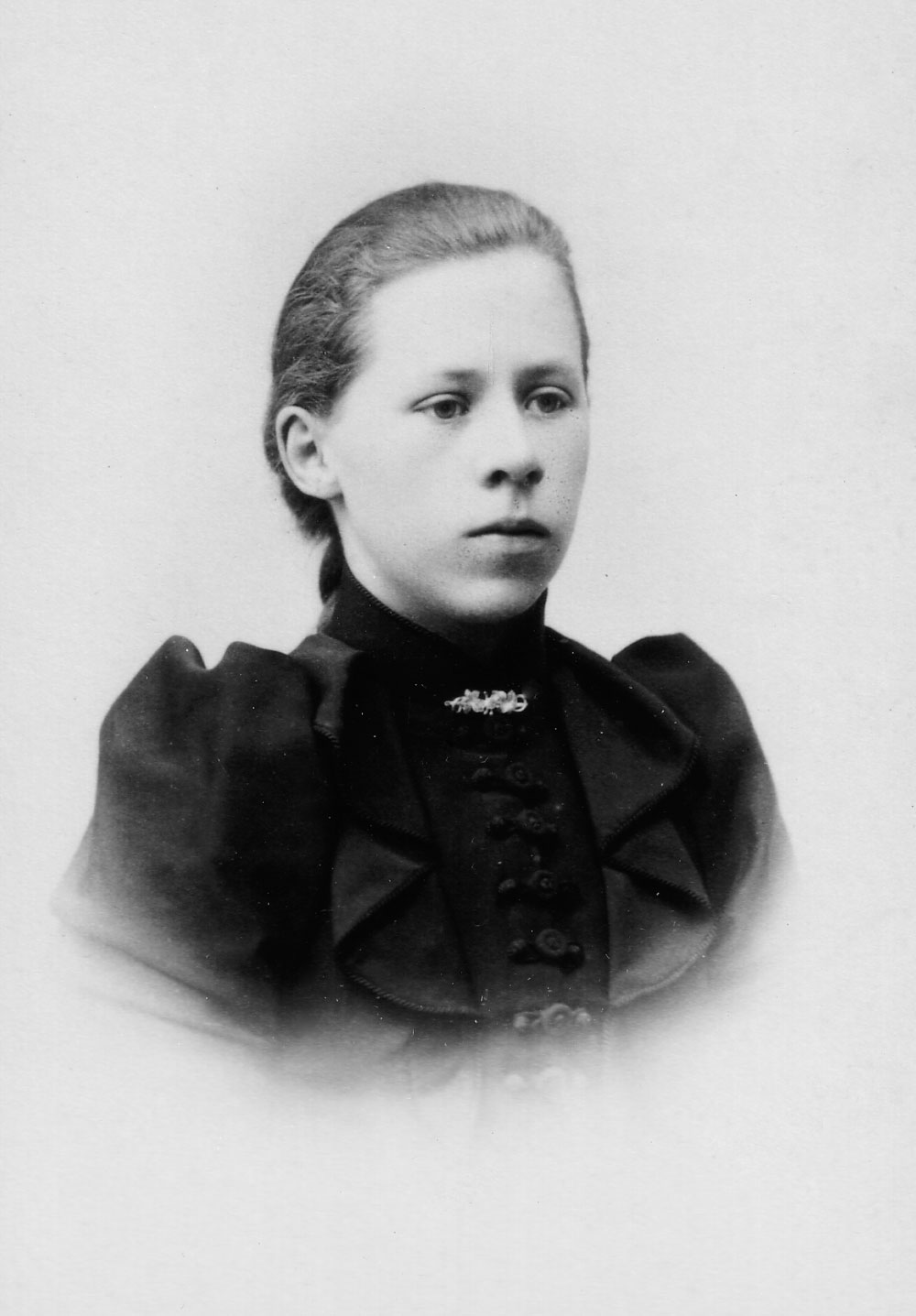 Porträtt i halvfigur av ung kvinna med svart klänning.