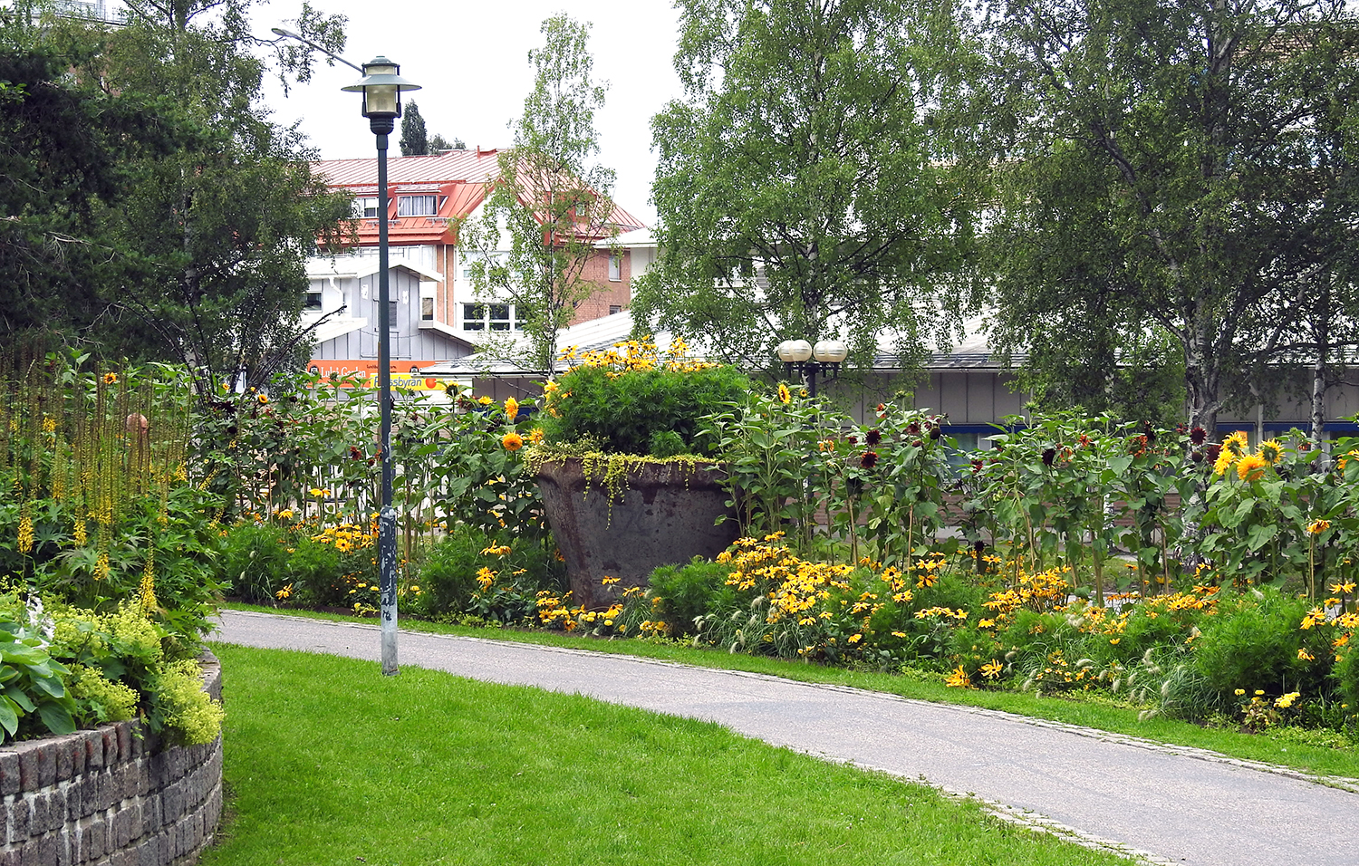 Bild på blomrabatter med stora kokiller med planteringar i. Står längs gång- och cykelvägen
