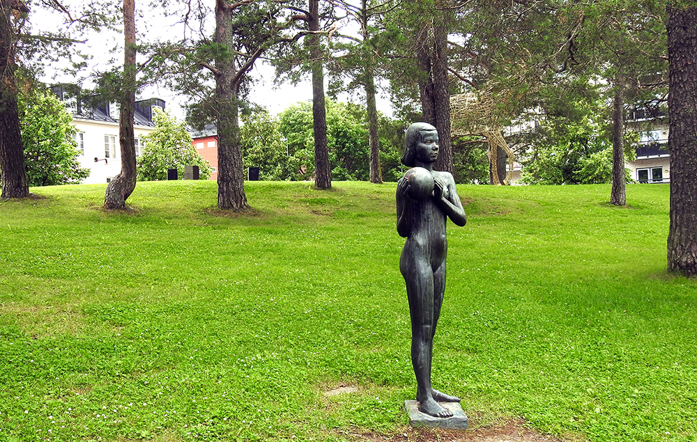 Bild med statyn av "Flicka med boll" som står i slänten på Floras kulle