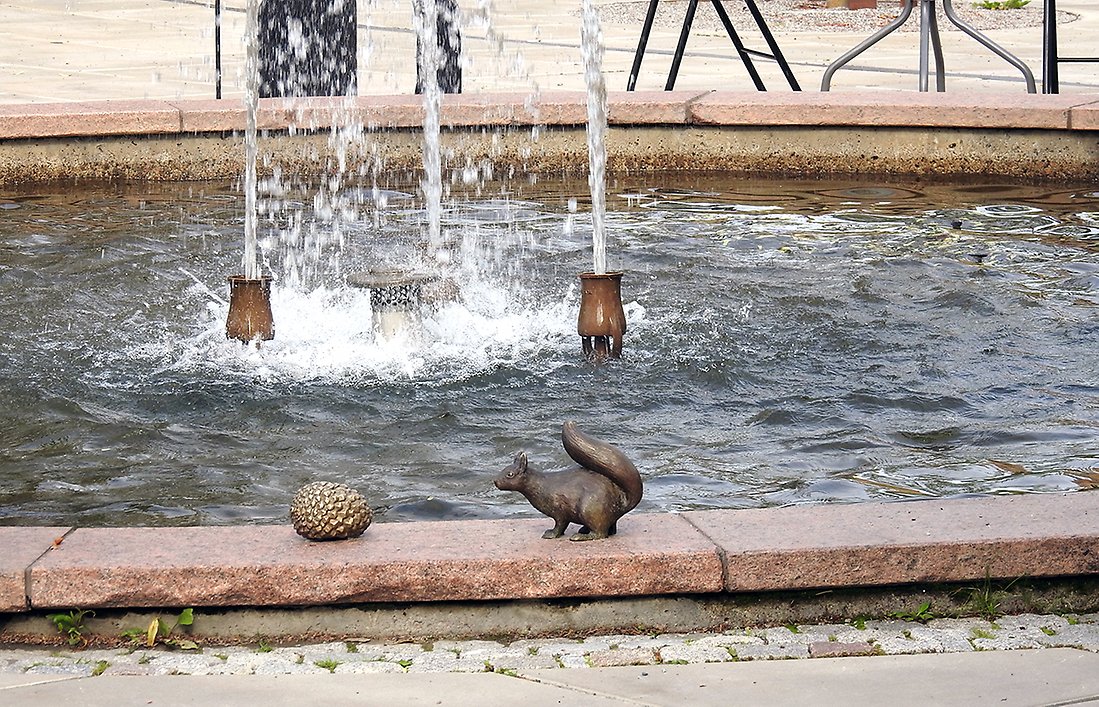 En ekorre och ett ekollon i sten pryder kanten på fontänen