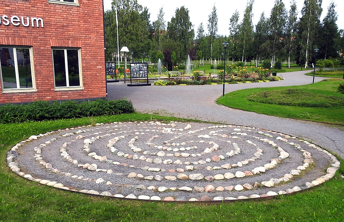Vid museet syns en stenlagd labyrint. I bakgrunden syns parken